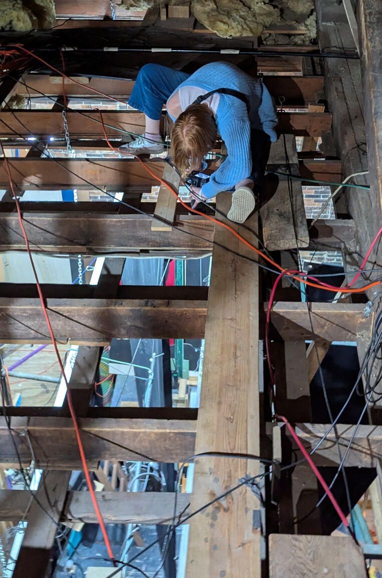 Bethany Nicole Muir taking load-in photos in the rafters for Clue: On Stage at MRT 2025